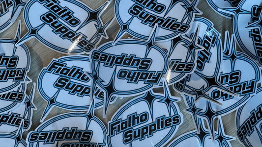 A pile of die-cut Fialho Supplies logo stickers on a table